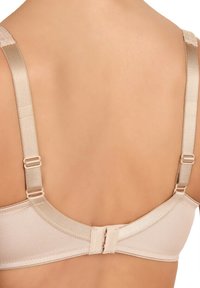 Soutien-gorge beige avec bretelles réglables, texture lisse et fermeture à crochet au dos. Design minimaliste sans motifs ni embellissements visibles.