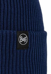 Navy blue knitted beanie with vertical ribbing, featuring a black label with white "Buff" logo sewn on the side. Soft texture.