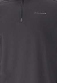 Zwarte longsleeve pullover met een kwart ritssluiting, gemaakt van soepel stof. Bevat een reflecterend logo "ENDURANCE" op de borst.
