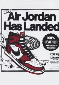 Raudonos ir baltos aukštosios sportinės avalynės dizainas su juodu swoosh. Tekstas sako "Air Jordan nusileido" ir turi užrašą "100% oda".