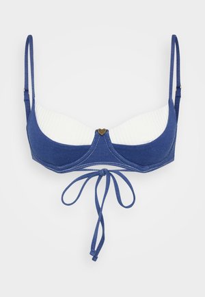 Haut de bikini en denim bleu avec un tissu à côtelé blanc, des bretelles ajustables et un nœud central. Présente un logo en forme de cœur à l'avant.