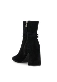 Botas de tobillo de ante negro con punta afilada, tacón de bloque y cremallera lateral, que presentan dos correas decorativas alrededor del tobillo.