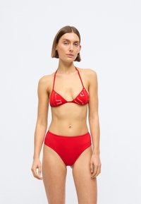 Κόκκινο μπικίνι σετ που διαθέτει τρίγωνη μπλούζα με λεπτές τιράντες και αντίστοιχο ψηλόμεσο σλιπ, κατασκευασμένο από λείο, ελαστικό υλικό.