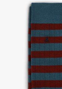 Calcetines a rayas en azul y burdeos, con una textura de canalé. Pequeño emblema de calavera y huesos cruzados bordado cerca de la parte superior.