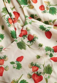 Bloemenstof met rode en groene aardbeien met witte bloesems op een crèmekleurige achtergrond, gemaakt van lichtgewicht materiaal met een zachte textuur.