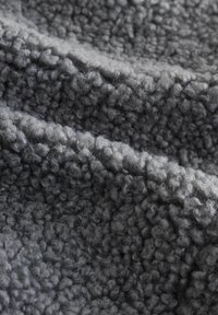 Tissu gris texturé avec une surface douce et moelleuse. Le matériau présente un design en boucles, créant une apparence chaleureuse et confortable.