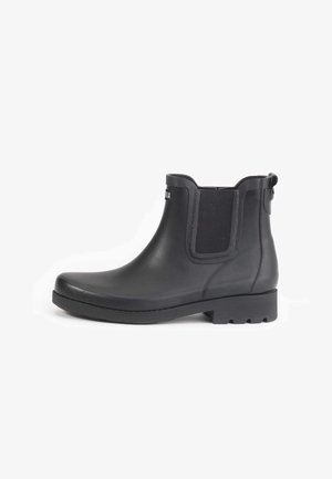 Black rubber ankle boot with elastic side panels, flat sole, and textured accents. Simple design with a rounded toe and heel pull tab.
