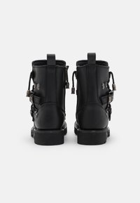 Botas de tobillo de cuero negro con un acabado mate, que presentan detalles de hebillas ajustables, tiradores y una suela de goma robusta.