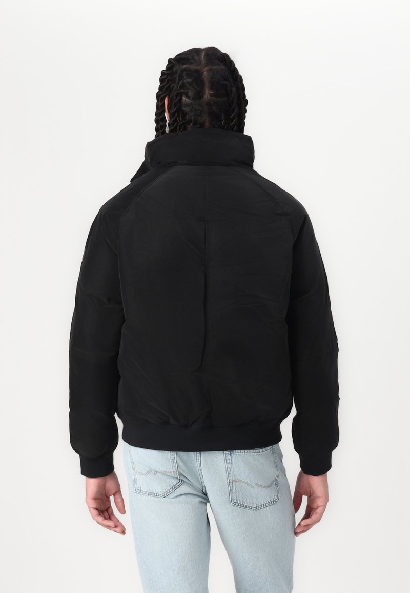 Chaqueta bomber acolchada negra con cuello alto, puños y cintura acanalados, textura de tela suave y un corte holgado.