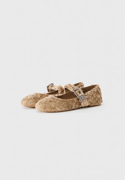 Fuzzy beige flats with a rounded toe, featuring a decorative silver buckle strap and a soft textured upper. Flat sole.