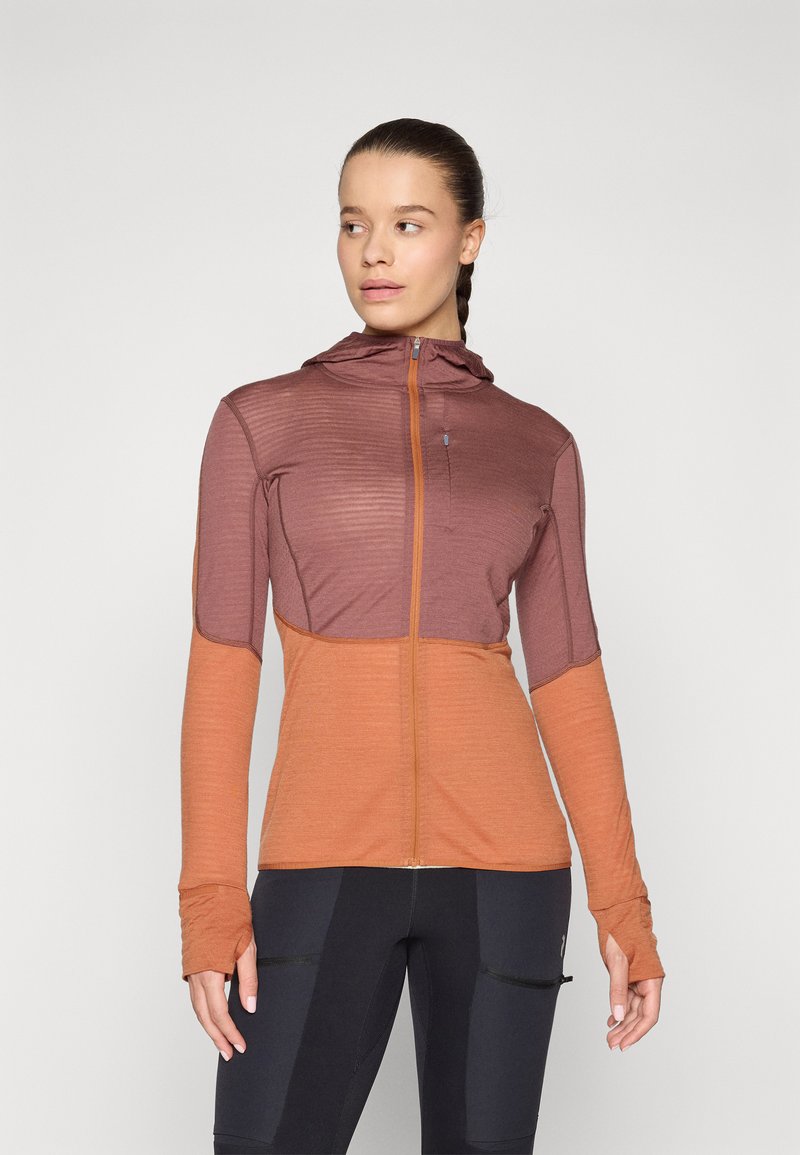Langärmlige Zip-Jacke in zwei Farben, Orange und Burgunderrot. Mit Kapuze, Streifen auf den Schultern und Daumenlöchern an den Bündchen. Weicher Stoff.