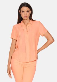 Korte mouwen perzikblouse met verticale plooien, knoopsluiting en een relaxed fit. Gemaakt van lichtgewicht, zachte stof.