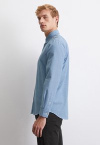 Light blue long-sleeve shirt with button-down collar, crafted from soft fabric, featuring a straight hem and buttoned cuffs.