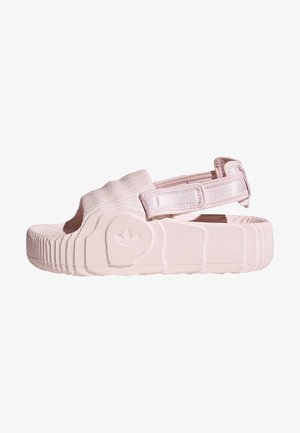 Sandale rose clair avec un design texturé, bout ouvert, sangle réglable et semelle rainurée avec un accent logo sur le côté.