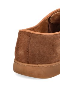Brązowe zamszowe trampki o zaokrąglonym kształcie, teksturowanej powierzchni i gumowej podeszwie. Wnętrze jest beżowe, o g ładkim wykończeniu i minimalnych detalach szycia.