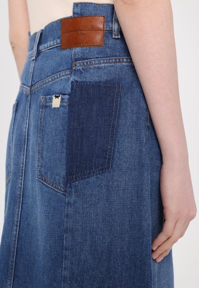 Denim skirt featuring varying shades, including a dark blue patch pocket. Brown leather branding at the waistband. Classic fit with subtle stitching.