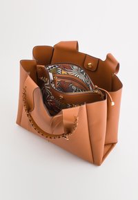 Brun læder tote bag med tekstureret ydre og flet håndtag. Indvendig har den et mønstret foer og en lynlåslomme til organisering.