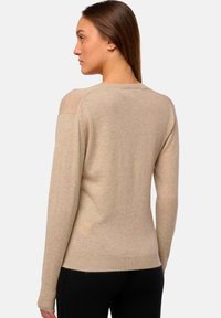 Beige Wollpullover mit langen Ärmeln, rundem Halsausschnitt und geripptem Saum. Glatte Textur, enganliegende Form und dezente Schulterdetails.