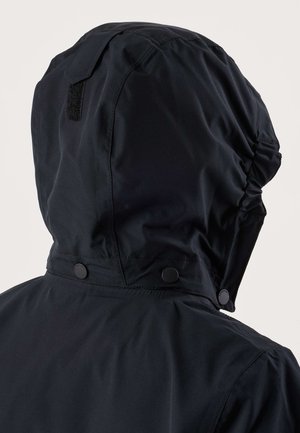 Čierna nepremokavá bunda s kapucňou zo zadnej strany, s nastaviteľnými cvokmi a elastickým detailom na kapucni.
