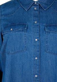 Denimhemd in einem tiefen Blauton mit Knopfleiste, spitzem Kragen und zwei Brusttaschen, die mit Metall-Druckknöpfen verschlossen sind.