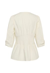 Blouse couleur crème à manches longues avec taille cintrée et manches légèrement bouffantes, vue de dos sur fond blanc.