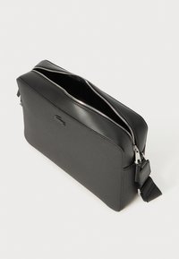 Borsa rettangolare nera con superficie testurizzata, chiusura con doppia zip e un elegante accento in pelle. Include una tracolla regolabile e accessori in argento.