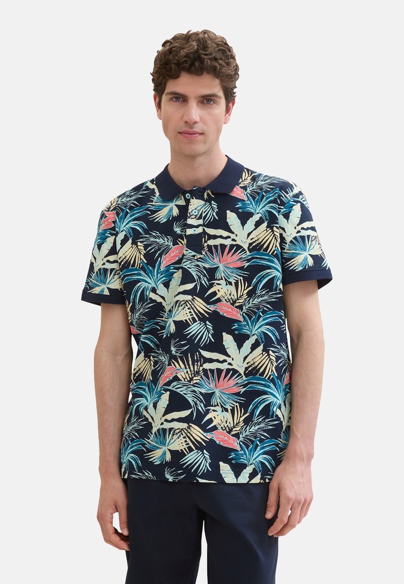 Korte mouw polo shirt in marineblauw met een kleurrijk tropisch bladerenpatroon. Beschikt over een effen donkere kraag en een drieknopenrij. Katoenmengsel.