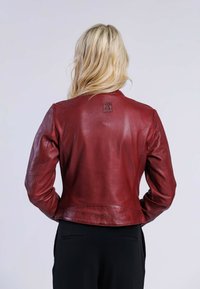 Veste en cuir rouge au design ajusté, présentant un léger éclat, des détails cousus et un petit logo embossé dans le dos.