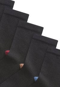 Chaussettes noires avec des bords côtelés ; chacune présente un accent coloré au niveau du talon—rouge, rose, beige et bleu. Texture lisse, longueur classique.