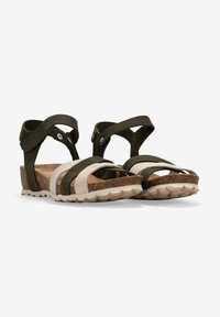 Sandalias verdes y beige con múltiples correas, plantilla de corcho, suela de goma y dos acentos circulares en la correa del tobillo. Diseño plano.