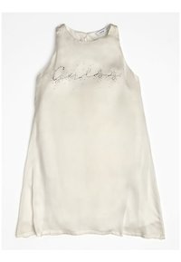 Hihaton, kermanvärinen mekko, jossa on sileä kangas ja hieman läpikuultava viimeistely. Edessä on strassikoristelu ja tekstikuvio.