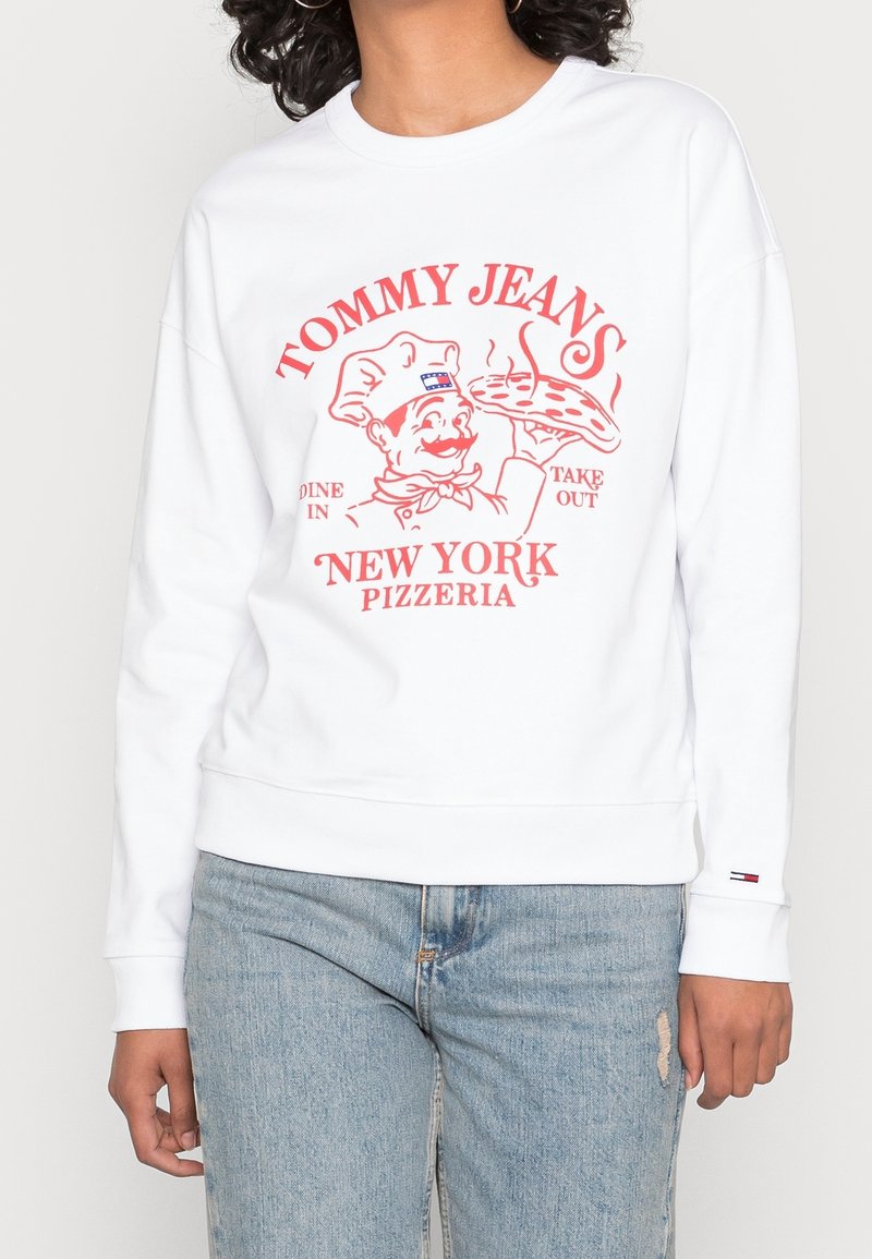 Felpa bianca con stampa grafica rossa di uno chef con una pizza, testo "TOMMY JEANS NEW YORK PIZZERIA" e polsini a coste.