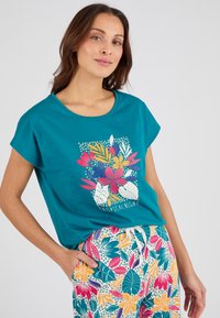 Teal katoenen t-shirt met korte mouwen en een bloemenprint met roze, gele en groene bladeren. Gecombineerd met bedrukt broek.