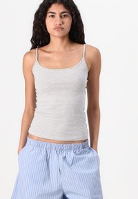 Gray cotton tank top with thin straps, fitted design, smooth texture, paired with light blue striped drawstring shorts.
