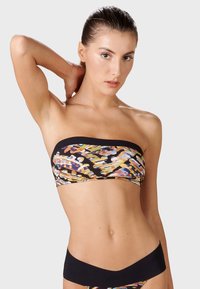 Svart bandeau-bikinitopp med färggärt abstrakt mönster. Slät textur, åtsittande design. Modell som visar plagget i en vinkel.