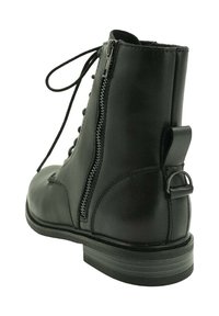 Botín negro de piel con cordones en la parte delantera, cremallera lateral, detalle en el talón y suela de goma plana con rayas texturizadas.