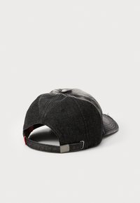 Svart denim caps med buet skygge, justerbar stropp bak og en falmet tekstur. Har en sølvfarget detalj.