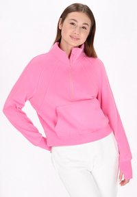 Rosa fleecepullover med kvartdragkedja vid halsen, raglanärmar och en framficka. Slät textur och kort design.