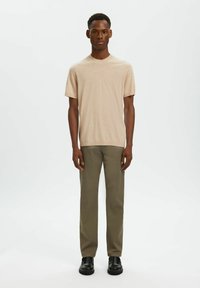 Pull en maille beige à manches courtes avec un col rond, assorti à un pantalon droit vert olive et des chaussures noires. Design simple et minimaliste.