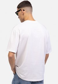 White cotton t-shirt with short sleeves, crew neck, and a relaxed fit. The fabric is smooth with a slightly matte texture.