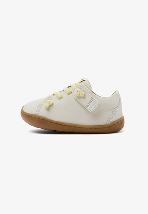 Skórzane sneakersy w kolorze kremowym z żółtymi sznurowadłami, zaokrąglonym noskiem, gumową podeszwą i przeszytymi detalami. Zapięcie na rzep z boku.
