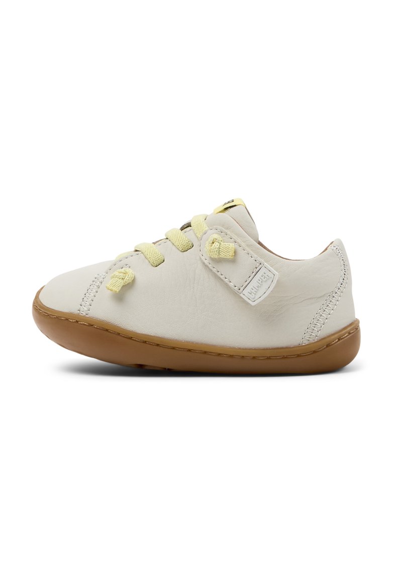 Sneaker in cuoio color crema con lacci gialli, punta arrotondata, suola in gomma e dettagli cuciti. Fascetta in velcro laterale per la chiusura.