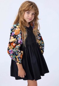 Black dress with a gathered skirt, featuring long sleeves in a vibrant floral pattern with orange, pink, and blue accents. Smooth fabric.