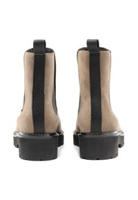 Cizme din suede până la gleznă, de culoare bej și neagră, cu panouri elastice pe lateral, tălpi negre groase și finisaj texturat. Include un tab de tragere în spate.