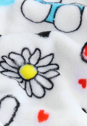 Fleecefilt med vit bas och svarta konturer av prästkragar, gula mittpunkter och små röda hjärtan. Mjuk textur, färgglada designelement.