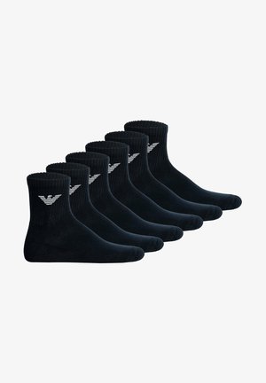 Chaussettes en coton noir, bordures côtelées, longueur cheville, avec un logo blanc sur le côté, vendues par lot de six paires.