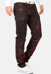 Jeans in denim nero e rosso con motivi testurizzati, tasche con zip e dettagli in borchie; design slim-fit con evidenti rifiniture a coste.
