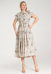 Beige Blumenkleid mit kurzen, Rüschensäumen, Knopfleiste, elastischem Bund und mehrlagigem Rock. Mit navyfarbenen Blumenmustern und einem lockeren Schnitt.