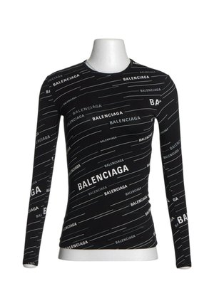 Zwart nauwsluitend shirt met lange mouwen op een mannequin, bedekt met herhalende witte "Balenciaga" tekst en subtiele diagonale lijnen.