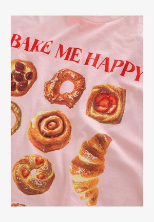 Rosa T-Shirt mit verschiedenen Gebäck-Grafiken, darunter Zimtschnecken, Croissants und Donuts, mit dem Schriftzug "BAKE ME HAPPY" in fettgedrucktem Rot.